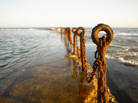 Rusting posts and chains along ocean pool