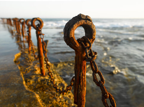 Rusting posts and chains along ocean pool
