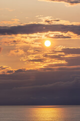 Golden sunset over a Norwegian sea, with dramatic clouds and glowing reflections shimmering on the...