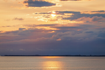 Golden sunset over a Norwegian sea, with dramatic clouds and glowing reflections shimmering on the...