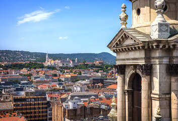 Panoramic view of Matthias Church and Fisherman's Bastion in Budapest, with Buda Hills in the background, captured from the dome of St. Stephen’s Basilica on a sunny summer day.