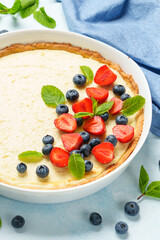 Tart with cheese and fresh berries on blue background.
