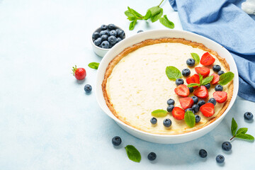 Tart with cheese and fresh berries on blue background.