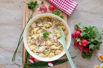 Healthy potato salad with yoghurt dressing, chives, red redish, onions and pickles in a bowl