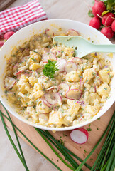 Healthy potato salad with yoghurt dressing, chives, red redish, onions and pickles in a bowl