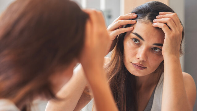 Young woman looking at his hair in the mirror