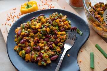 Delicious vegan salad with red lentils, kidney beans and yellow bell peppers on a plate