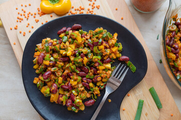 Delicious vegan salad with red lentils, kidney beans and yellow bell peppers on a plate