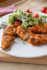 Small chicken schnitzel fresh and homemade cooked with a fresh salad on a plate