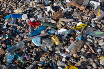 Plastic bottles and garbage polluting a pebble beach