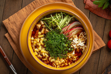 Okroshka soup with kvass vegetables and herbs in yellow bowl