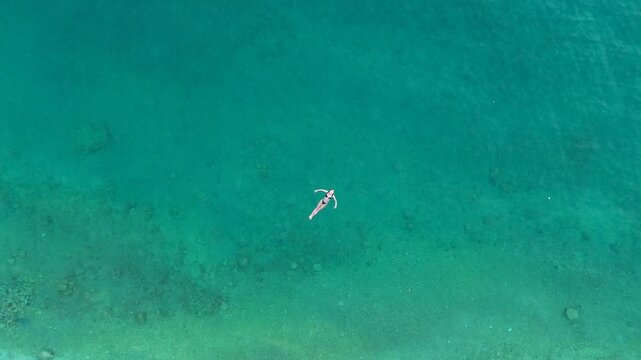 4K Drone Footage of Model Floating on Clear Blue Water at Brela Beach, Croatia