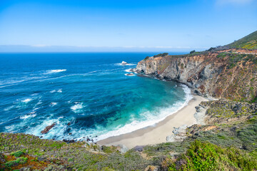 Iconic Bixby Creek Bridge stretches across the cliffs of Big Sur along Highway 1, with waves crashing below and lush hills meeting the Pacific Ocean on California's dramatic coast