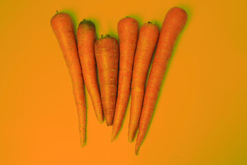 Fresh Orange Carrots Against a Bright Orange Background Displayed in a Group
