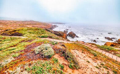 Coastal bench view at the edge of the Pacific along Highway 1 in California, surrounded by lush...