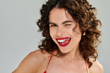 Charming young woman exuding summer vibes with stylish red outfit and playful expression