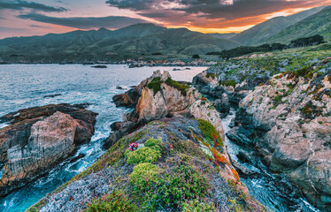 Scenic coastal view at Garrapata State Park near Big Sur, California, showcasing rugged cliffs, vibrant plants, and the Pacific Ocean along the iconic Highway 1 on a clear spring day