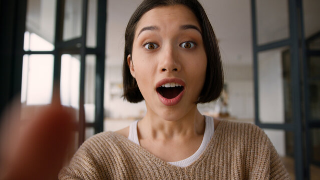 Point of view POV webcam mobile phone happy amazed excited girl Hispanic latin woman astonish wonder shock emotions read good news online app win typing message fingers touch screen display smartphone