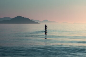 Person paddleboarding on a tranquil ocean in the evening