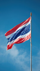 Thai flag waving against clear blue sky, symbolizing national pride and freedom