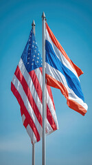 Two flags, American flag and Thai flag, flapping against clear blue sky