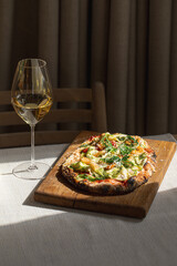 Pinsa with shrimp, zucchini and pesto on wooden board with wine