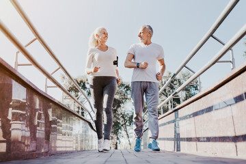 Full length of senior couple runners training outdoors, running jogging outside in city center,...