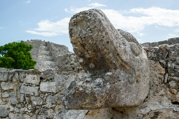 Ancient Stone Serpent Head Sculpture (Kukulkan) in Ruins with Tree and Sky Background, Mayapan,...