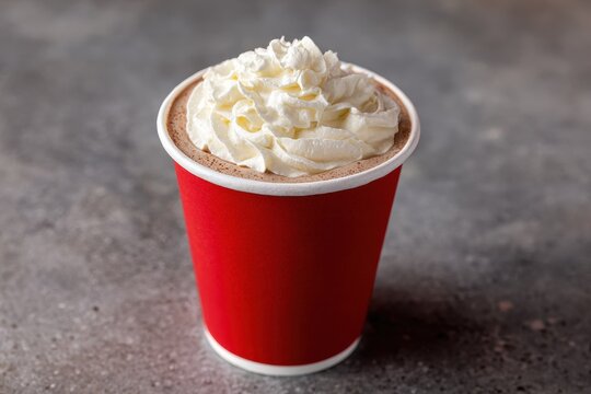 Red cup with whipped cream on a counter holding a mocha latte
