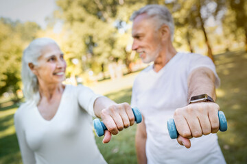 Sport equipment for training. Smiling caucasian man and woman on retirement lifting dumbbells...