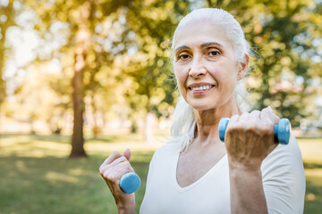 Park, dumbbells and portrait of senior woman for workout, wellness and exercise outdoors. Retirement, happy and mature person with weights in nature for fitness, health and training for mobility