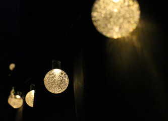 Warm decorative string lights glowing in the dark. Spherical bulbs filled with bubbles create a...