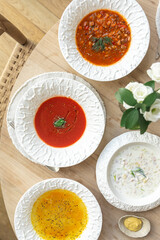 Assorted soups served in white bowls on wooden table