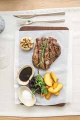 Grilled steak with rosemary garlic and potato wedges on serving board