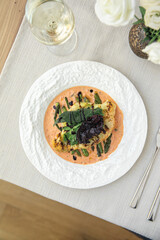 Cauliflower steak with asparagus and sauce on white plate