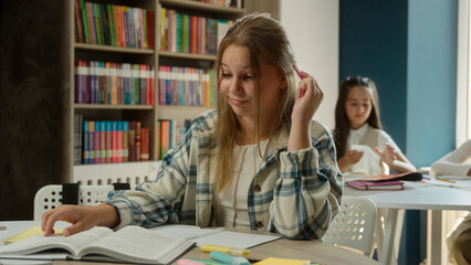 Bored sad frustrated teen kid Caucasian girl pupil schoolgirl upset learner at desk tired lazy exhausted student child studying lesson reading boring book learning in classroom school study textbook