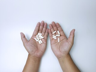 Hands Holding White Pills on White Background
