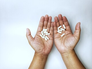Hands Holding White Pills on White Background