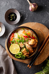 A bowl of glass or cellophane noodles with Asian caramelized chicken breast on a table vertical photo