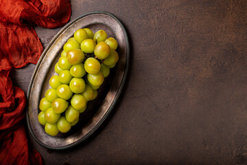 A vibrant and fresh bunch of muscat green grapes on a metal tray top view, healthy snack, copy...