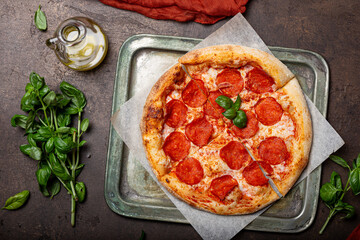 Homemade italian pizza with mozzarella, pepperoni sausages, on a dark background top view