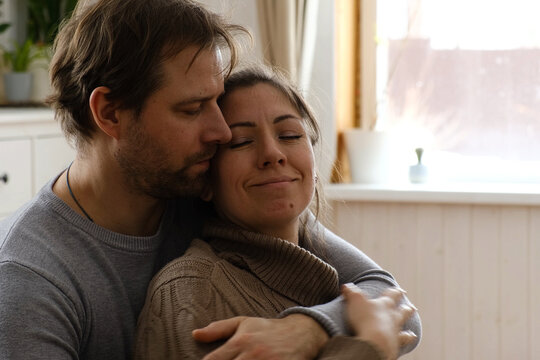 Mature couple hugging hugging each other kissing at home bedroom. Intimate Moment. Tender embrace shared between a loving middle age man and woman, husband and wife. Deep love. Low key, cinematic.
