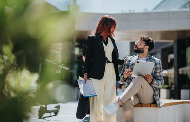 Two professionals collaborate in a contemporary cityscape, focused and engaged in discussion.