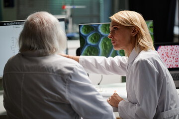 Caucasian middle aged woman discussing scientific data with Caucasian senior man in laboratory...