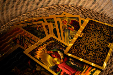 Tarot cards with gold accents lie on burlap. 