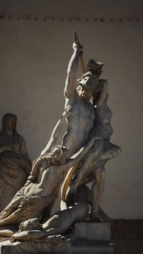 A statue of a man holding a sword and two women. The statue is of a man and two women, one of which is being attacked by the man