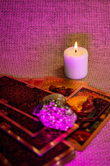 Tarot cards with gold designs of a King and Queen lie on woven fabric. Rock crystal, pyrite, and a...