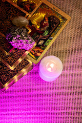Tarot cards with gold designs of a King and Queen lie on woven fabric. Rock crystal, pyrite, and a...