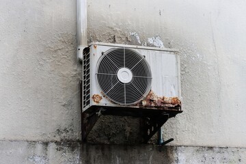 Old and rusty air conditioner condensing unit on wall hanger