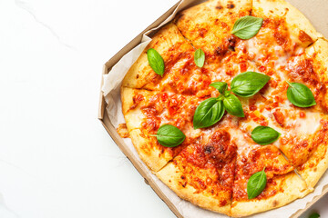 Pizza Margarita in a cardboard box on white background.